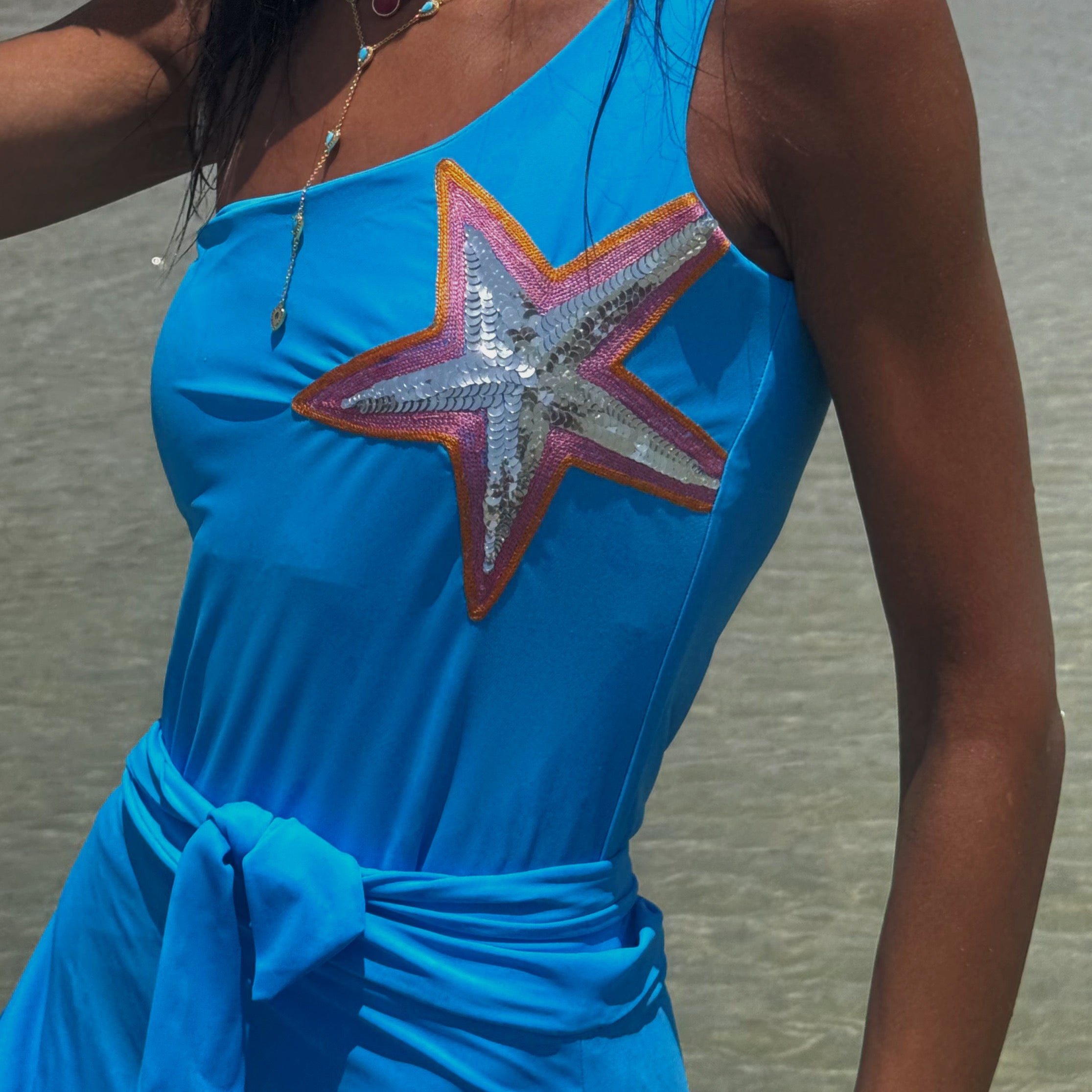 Woman wearing a blue dress with a star design on a beach.