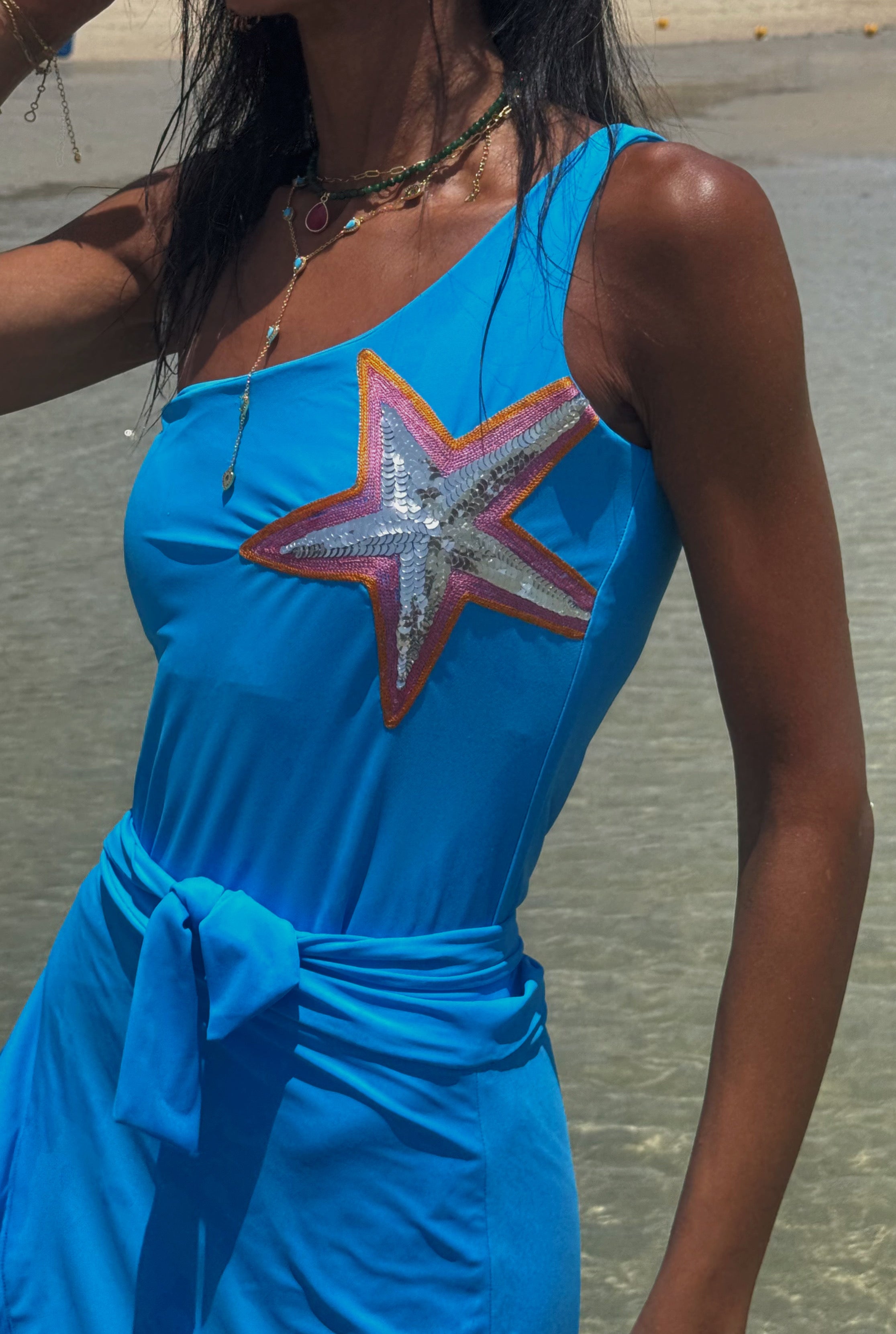 Woman wearing a blue dress with a star design on a beach.